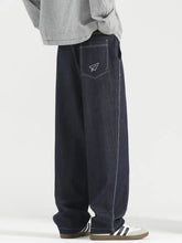 Men’s plus size wide leg dark blue denim jeans with white stitching and paper airplane embroidery on back pocket view
