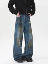 Men’s plus size wide leg jeans in faded blue and olive green denim with distressed paint splatter design