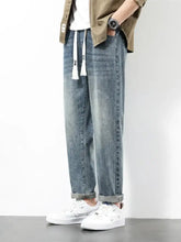 Men’s plus size wide leg light-wash denim jeans with relaxed fit white drawstrings and rolled cuffs visible from the front