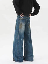 Men’s plus size wide leg jeans in medium blue denim with distressed paint-splatter detailing on back pockets viewed from rear