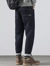 Men’s dark indigo denim pocketed loose fit jeans with rolled cuffs and subtle white stitching for all-day comfort