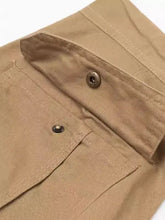 Close-up of tan cotton mens pocketed pants with brass snaps and stitching