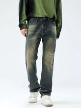 Men’s relaxed fit jeans in dark-wash denim with a faded, distressed look and subtle greenish-yellow thigh staining
