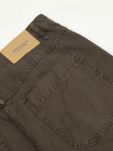 Men’s relaxed fit dark olive green denim jeans with tan leather brand label on waistband featuring unique creative collection