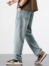 Men’s relaxed fit light-wash denim jeans with a small brown patch on the thigh in a casual style