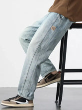 Men’s relaxed fit light-wash denim jeans with a straight-leg cut and small brown patch on the thigh