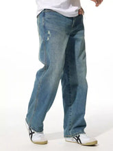 Men’s relaxed fit wash jeans in blue denim with a distressed faded wash and subtle frayed details on the thigh