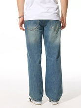 Men’s relaxed fit wash jeans in blue denim with a faded worn-in look and classic back pockets shown from the back side