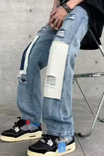 Men’s light-wash denim ripped patchwork wide leg jeans with distressed patches and white and navy fabric accents