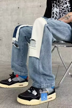 Men’s light-wash ripped patchwork wide leg jeans with distressed knees and contrasting white fabric panels