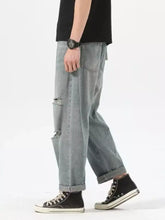 Men’s light-wash ripped relaxed fit jeans with distressed thighs and rolled cuffs in denim material