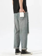 Men’s light-wash denim ripped relaxed fit jeans with a tapered silhouette and distressed cuffs