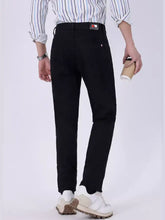 Black slim fit jeans in denim paired with a subtle striped shirt and white sneakers for a modern casual look