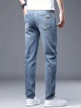 Men’s slim fit jeans in light-wash denim with subtle fading and a brand patch on the back pocket showing the back side