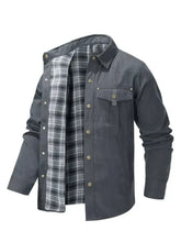 Men’s long sleeve jacket in dark gray flannel with black and white plaid lining, brass buttons, and chest pocket