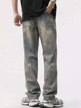 Men’s gray distressed denim star wide leg jeans with faded wash and scattered white star appliqués visible