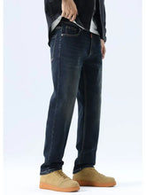 Men’s straight leg washed dark-wash denim jeans with subtle fading paired with tan suede sneakers