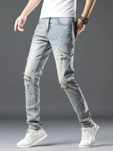 Men’s vintage distressed light wash skinny jeans with ripped details and subtle paint-splatter accents