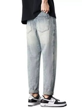 Men’s vintage distressed straight leg jeans in light-wash denim with a relaxed tapered fit and rolled cuffs