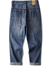 Men’s blue denim jeans with vintage wash loose fit and rolled cuffs showcasing a faded wash style