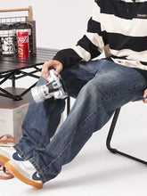 Silver-bodied vintage-style camera with black accents and textured grip featured with men’s vintage wash loose fit jeans