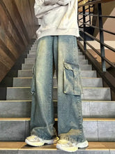 Men’s vintage wash wide leg cargo jeans in faded blue denim with large flap pockets and subtle distressing