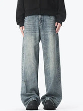 Men’s vintage wash wide leg jeans in faded blue denim with subtle distressing and raw hem detailing