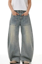 Men’s vintage wash wide leg jeans in faded light blue denim with prominent front pockets and subtle distressing