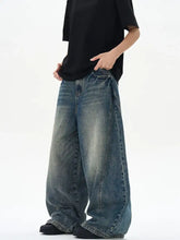 Men’s vintage wash wide leg jeans in faded blue denim with subtle distressing and raw hem detailing