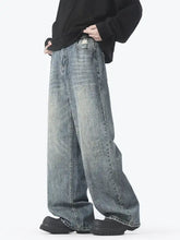 Men’s vintage wash wide leg jeans in faded blue denim with intentional distressing and frayed hems