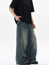 Men’s vintage wash wide leg jeans in faded blue denim with subtle distressing and raw hem detailing