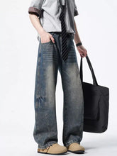 Men’s vintage wash wide leg jeans in faded blue denim with visible stitching details and a relaxed fit