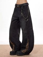Men’s vintage wide leg black denim jeans with snake print fabric accents and chain detail along the outer seams