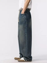 Men’s dark-wash relaxed fit jeans in denim with a wide-leg cut and elastic waistband with white drawstrings