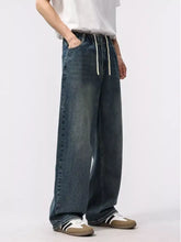 Men’s dark-wash denim relaxed fit jeans with wide-leg cut and white drawstrings at elastic waistband