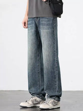 Men’s wash relaxed fit jeans in faded medium-blue wide-leg denim with subtle whiskering and stitching details