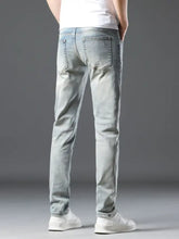 Men’s wash slim fit jeans in light-wash denim with slim fit, subtle fading, and classic stitched back pockets shown from back side