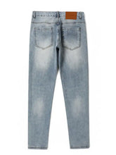 Men’s wash slim fit light-wash denim jeans with a faded distressed look and brown leather brand patch on the waistband