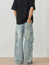 Men’s light-wash denim cargo jeans featuring multiple flap pockets and a relaxed wide leg cargo design