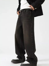 Men’s black wide leg denim jeans with faded distressed finish and visible stitching along the seams