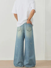 Men’s light-wash denim wide leg jeans with subtle distressing and relaxed oversized fit for casual wear
