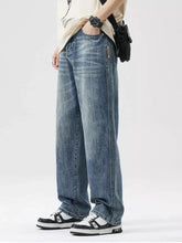 Men’s medium-wash blue denim wide leg jeans with a relaxed straight-leg cut and subtle fading details