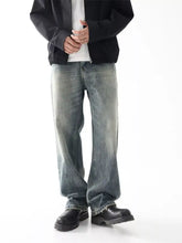 Men’s wash wide leg relaxed fit jeans in faded blue denim with subtle distressing and raw hem detailing