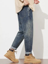 Men’s dark-wash denim washed loose fit jeans with relaxed fit and rolled cuffs paired with tan suede boots