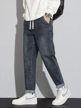 Men’s dark-wash denim relaxed fit cuffed jeans with rolled cuffs and white drawstring tabs at the waist