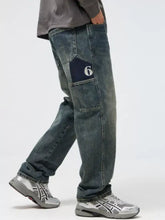 Men’s dark-wash denim relaxed fit jeans with a navy blue thigh pocket patch embroidered with number 6