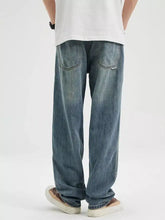 Men’s washed relaxed fit jeans in faded blue denim with wide legs subtle distressing and classic stitching visible