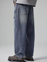 Men’s washed relaxed wide-leg jeans in faded blue denim with a pearl chain detail on the waistband