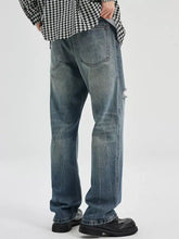 Men’s washed ripped bootcut jeans in blue denim with a distressed faded look and subtle frayed detail on the right leg