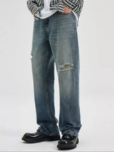 Men’s washed ripped bootcut jeans in distressed blue denim with faded wash and frayed tear at the knee